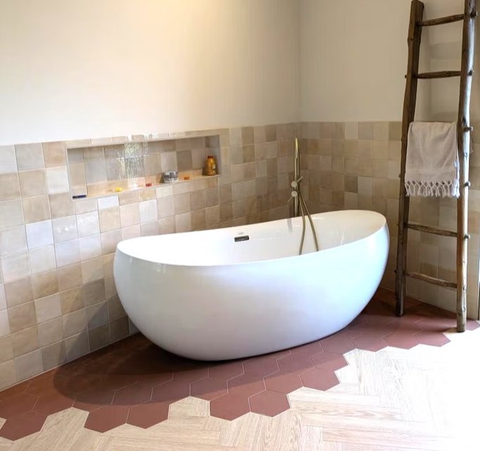 Salle de bain avec baignoire îlot et carrelage terracotta